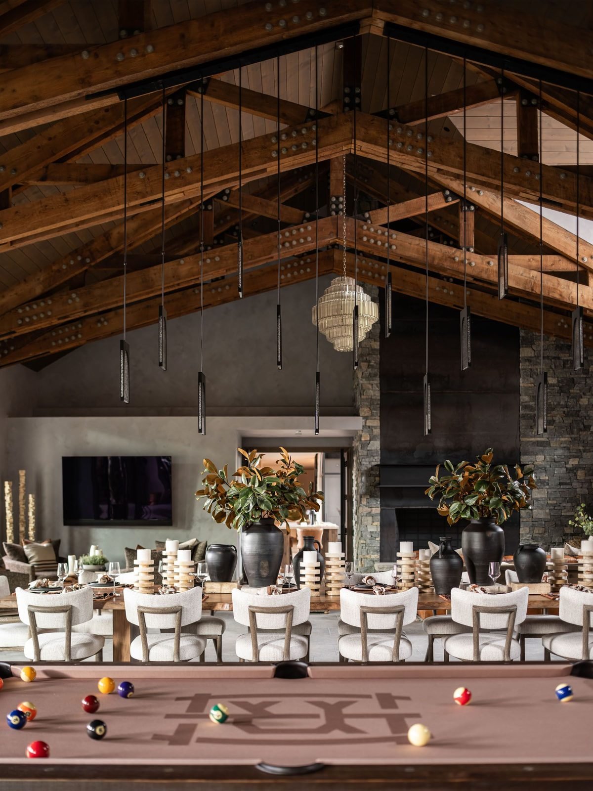 Billiards table beneath a grand dining hall with pendant lighting