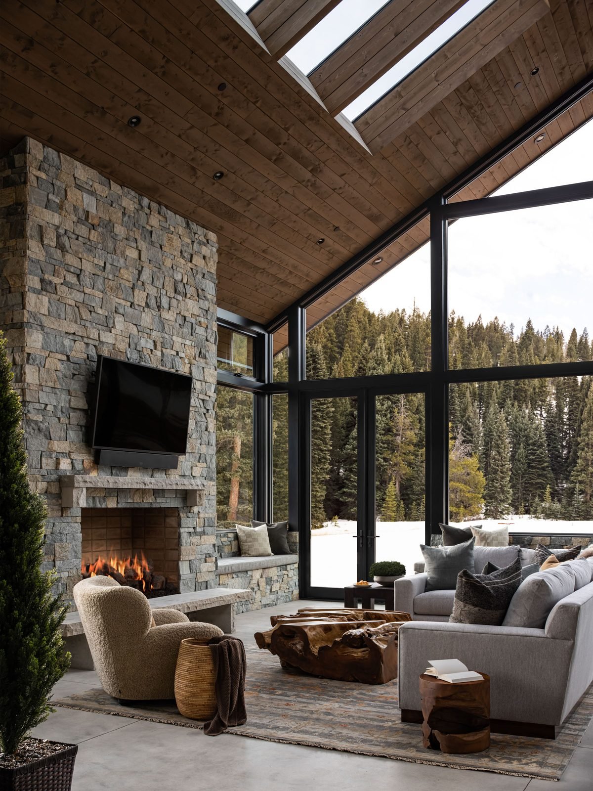 Great room with lit fireplace and forest view