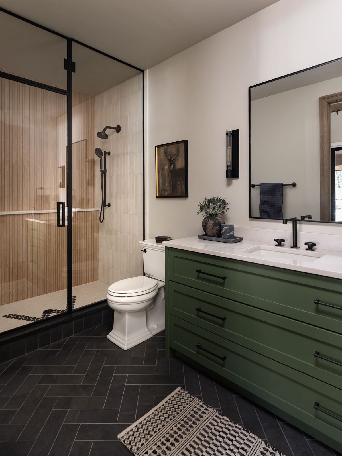 Guest bath with green vanity and herringbone tile